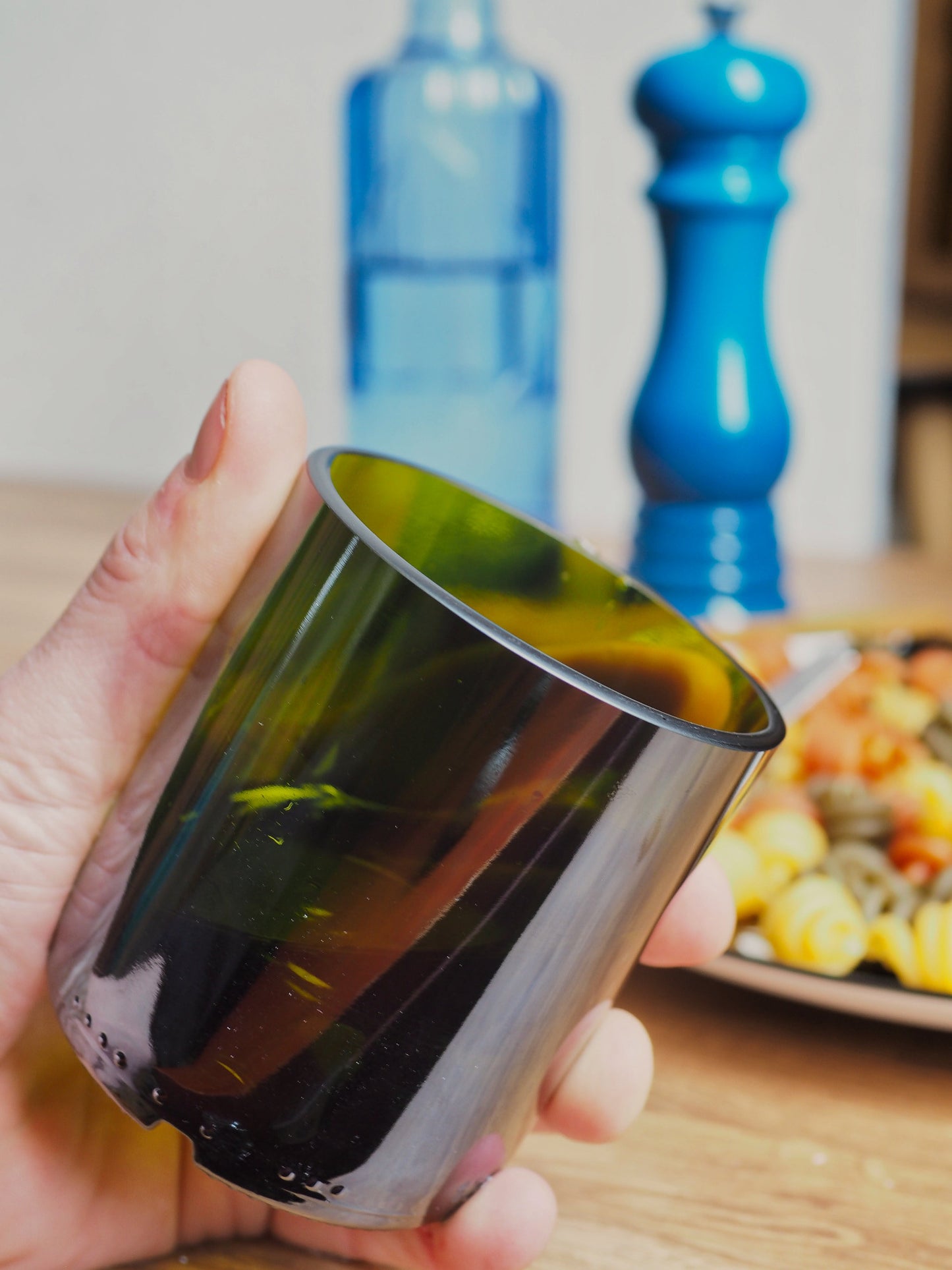 Verre vert recyclé artisanal, découpé dans une bouteille en verre. Présentation du verre pris en main. Produit écologique et design, idéal pour une décoration durable ou un cadeau écoresponsable.